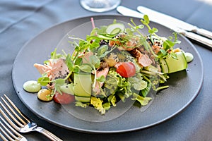 Caesar salad with salmon on black dish
