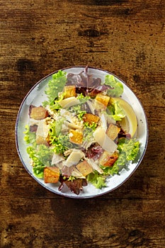 Caesar salad, shot from the top on a dark rustic wooden background