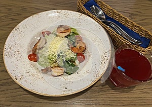 Caesar salad with shrimps and a glass of fruit drink