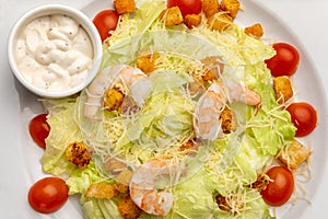 Caesar salad with shrimps on a white plate