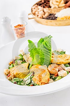 Caesar salad on a white plate consisting of chicken