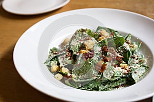 Caesar Salad on white plate on the wood table in restaurant