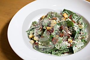 Caesar Salad on white plate on the wood table in restaurant