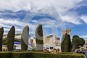 Caesars Palace Hotel, Casino and resort along the Las Vegas strip with tall lush green trees, water fountains, statues, blue sky