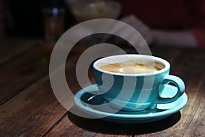 Hot black coffee in blue ceramic cup on wooden table background. photo