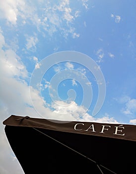 CAFE - cafe sign on a black umbrella against the blue sky and clouds