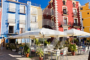 Cafe, colorful houses and palms on the street in Villajoyosa, Spain on a sunny day