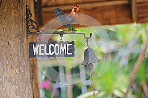 Cafe entrance sign `Welcome` and the bell white green blur background. Lovely coffee cafe in Chiangmai, Thailand.