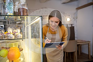 Cafe owner checking desserts in a display case
