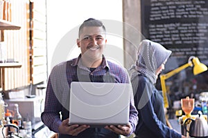 Cafe owner at his coffee shop using tablet computer. his partner sitting in a background