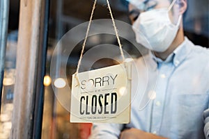 Cafe or restaurant and business reopen after Coronavirus quarantine is over. Man with face mask turning a sign from closed to open