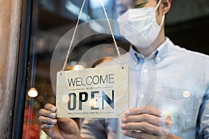 Cafe or restaurant and business reopen after Coronavirus quarantine is over. Man with face mask turning a sign from closed to open