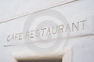 cafe restaurant sign on stoned wall of building facade in the street