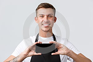 Cafe and restaurants, coffee shop owners and retail concept. Close-up of cheerful handsome salesman showing smartphone