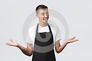 Cafe and restaurants, coffee shop owners and retail concept. Handsome friendly smiling salesman, waiter in black apron