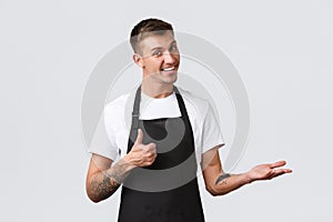 Cafe and restaurants, coffee shop owners and retail concept. Handsome smiling blond salesman, waiter or barista pointing