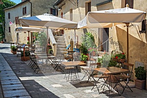 Cafe tables and chairs in a street in the village of Bagno Vignoni, Tuscany Italy