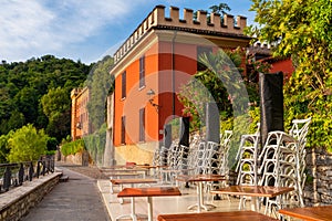 Cafe tables outside on embankment with colorful villa on Como lake in outdoor restaurant with nobody, Lenno comune photo
