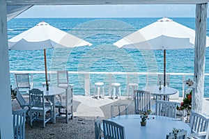 Cafe tables under sunshade umbrellas on a platform next to an ocean