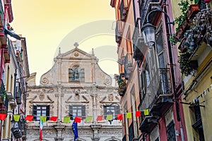 Cagliari San Michele Jesuit Catholic church facade around historic buildings with wooden window shutters and iron balconies in