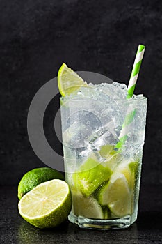 Caipirinha cocktail in glass on black stone.
