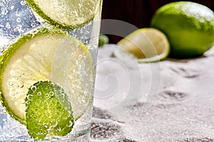 Caipirinha, Mojito cocktail, vodka or soda drink with lime, mint and straw on sand background. Close-up