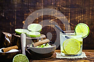 Caipirinha, a typical Brazilian cocktail made with lemon, cachaÃ§a, sugar and ice, Ingredients on the side. Sugar, Cinnamon,