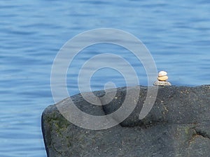 Cairn on a large black rock by the ocean or shore line