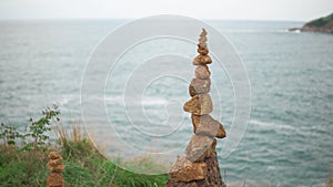 A cairn is stands on top of a cliff against the blue sea. Heap of stones close-up
