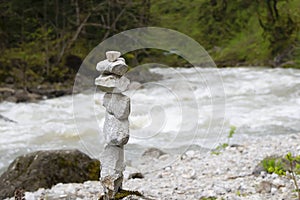 Cairn, stone sculpture, against the mountain river water. White stones of the pyramid in the forest symbolizing zen, harmony