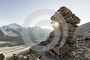 Cairn with sunray in the alps with glacier in the background