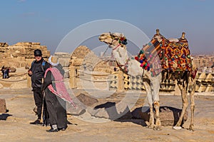 CAIRO, EGYPT - JANUARY 28, 2019: Camel handler with a tourist in front of the Pyramid of Khafre in Giza, Egy
