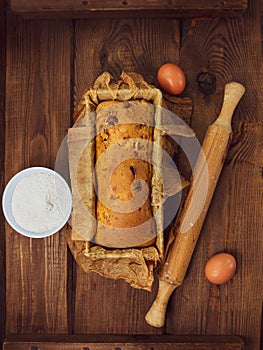 Cake in baking mold with rolling pin rural rustic wooden background flat lay. Pastry dough recipe ingredients with eggs