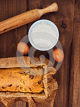 Cake in baking mold with rolling pin rural rustic wooden background flat lay. Pastry dough recipe ingredients with eggs