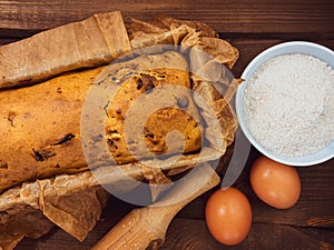 Cake in baking mold with rolling pin rural rustic wooden background flat lay. Pastry dough recipe ingredients with eggs