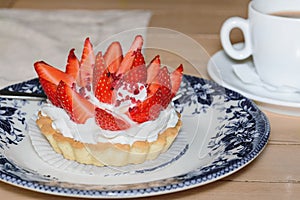 Cake basket with buttercream and fresh strawberries on top. Cupcake dessert and coffee in a cafe