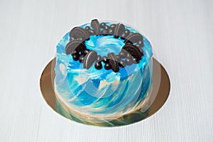 Cake with blue watercolor on cream with chocolate decoration. Peanuts in chocolate.