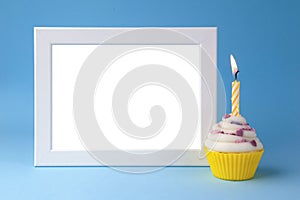 Cake with candle and photo frame on blue background closeup