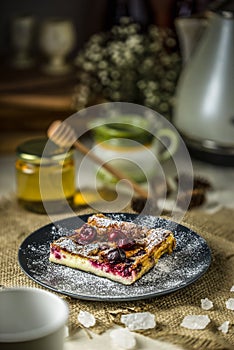 Cake with cherry clafouti on a dark plate. Klafuti with honey