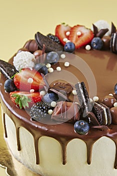 Cake decorated with strawberry and chocolate on yellow background