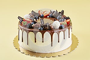 Cake decorated with strawberry and chocolate on yellow background