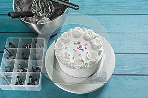 Cake frosting making baking mixer bowl, and box of piping nozzles on kitchen table