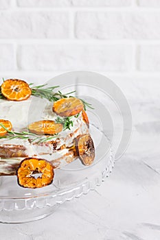 Cake on glass stand decorated with rosemary dried mandarin slice