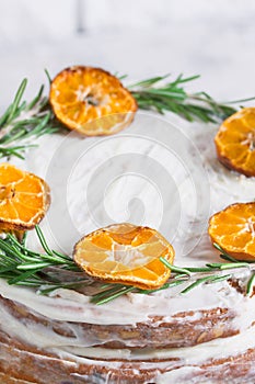 Cake on glass stand decorated with rosemary dried mandarin slice