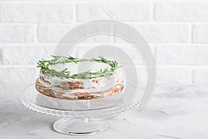 Cake on glass stand decorated with sprigs of rosemary