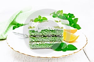 Cake with orange and mint in plate on light wooden board