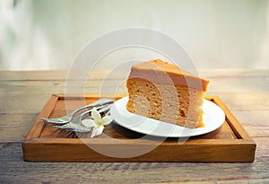 Cake on plate with fork and flower on wood table vintage tone.