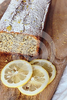 Cake with poppy seeds and lemon zest, sprinkled with powdered sugar. Cupcake with lemon on a wooden board.