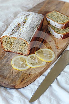 Cake with poppy seeds and lemon zest, sprinkled with powdered sugar. Cupcake with lemon on a wooden board.