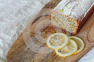 Cake with poppy seeds and lemon zest, sprinkled with powdered sugar. Cupcake with lemon on a wooden board.